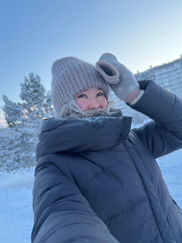 Woman walks dog through snowy Krasnoyarsk streets in winter