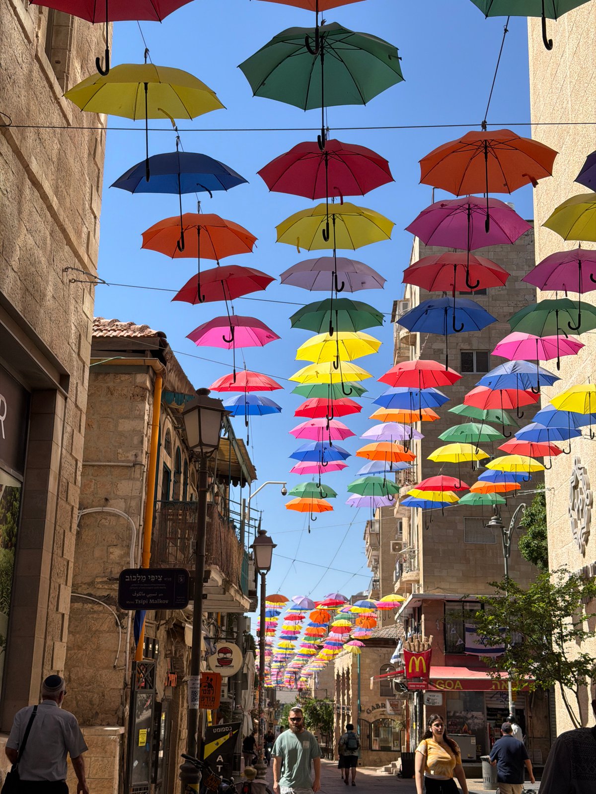 Colorful umbrella canopy installation lines a Jerusalem pedestrian street