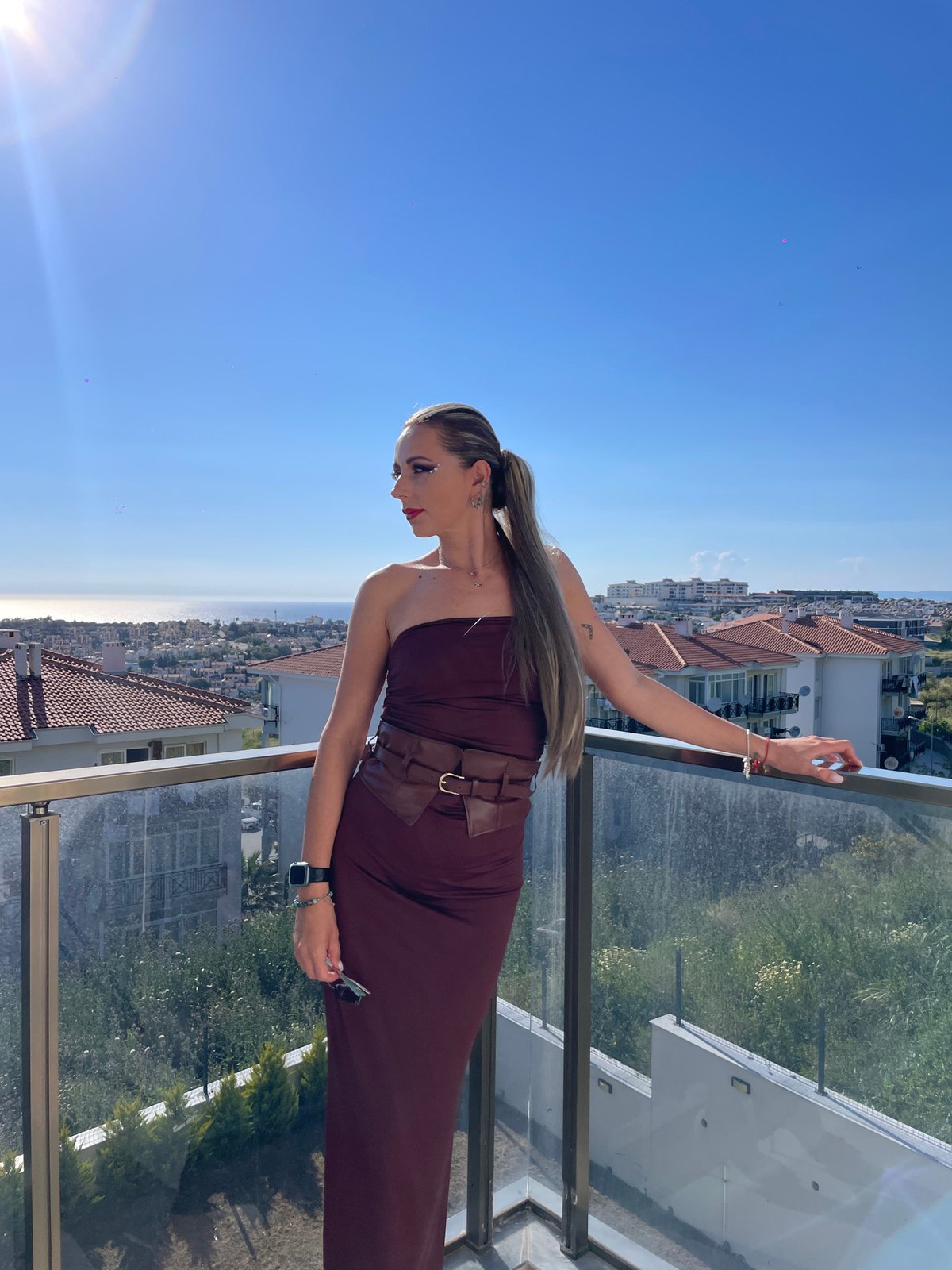 Woman in maroon dress spotted on Kuşadası balcony with phone