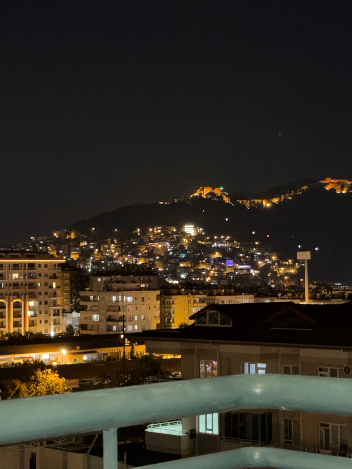 Balcony night with city views, poolside lights, and wine.