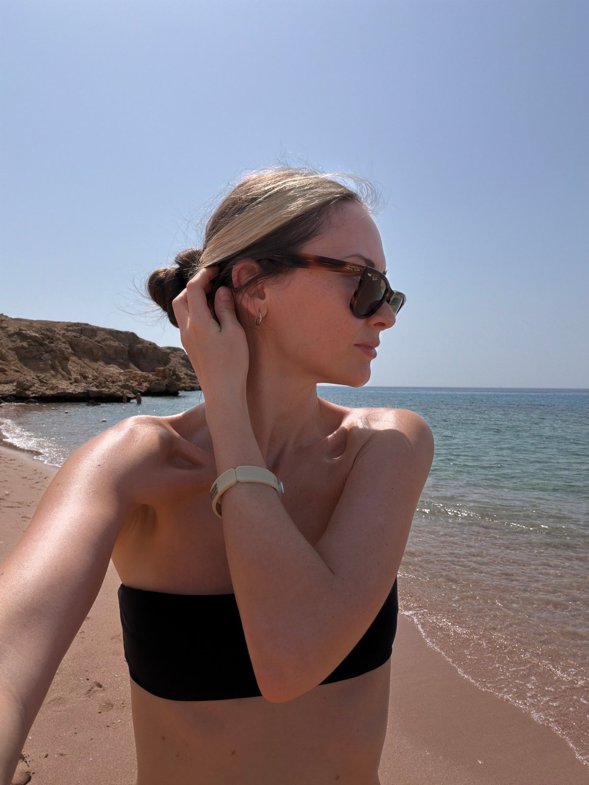 Woman enjoys morning sunbath on unidentified beach