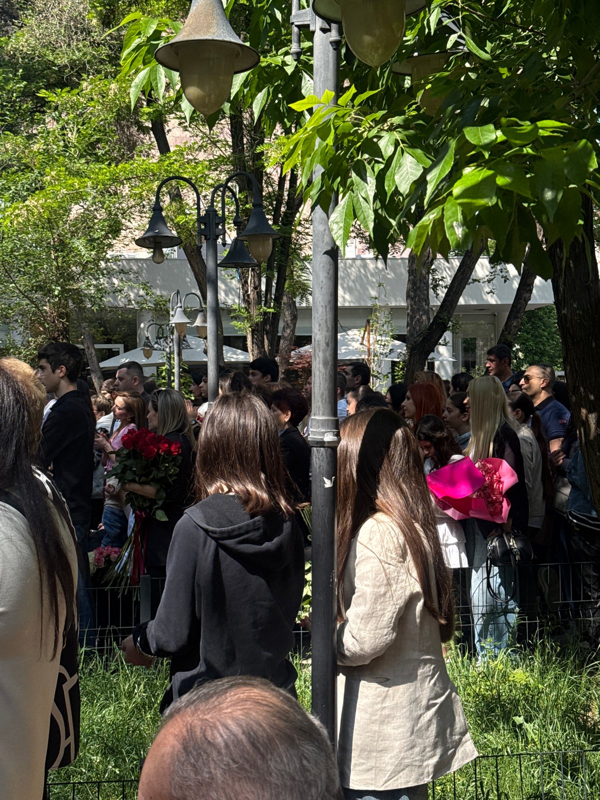 Flower-bearing crowds gather at decorated building in Yerevan