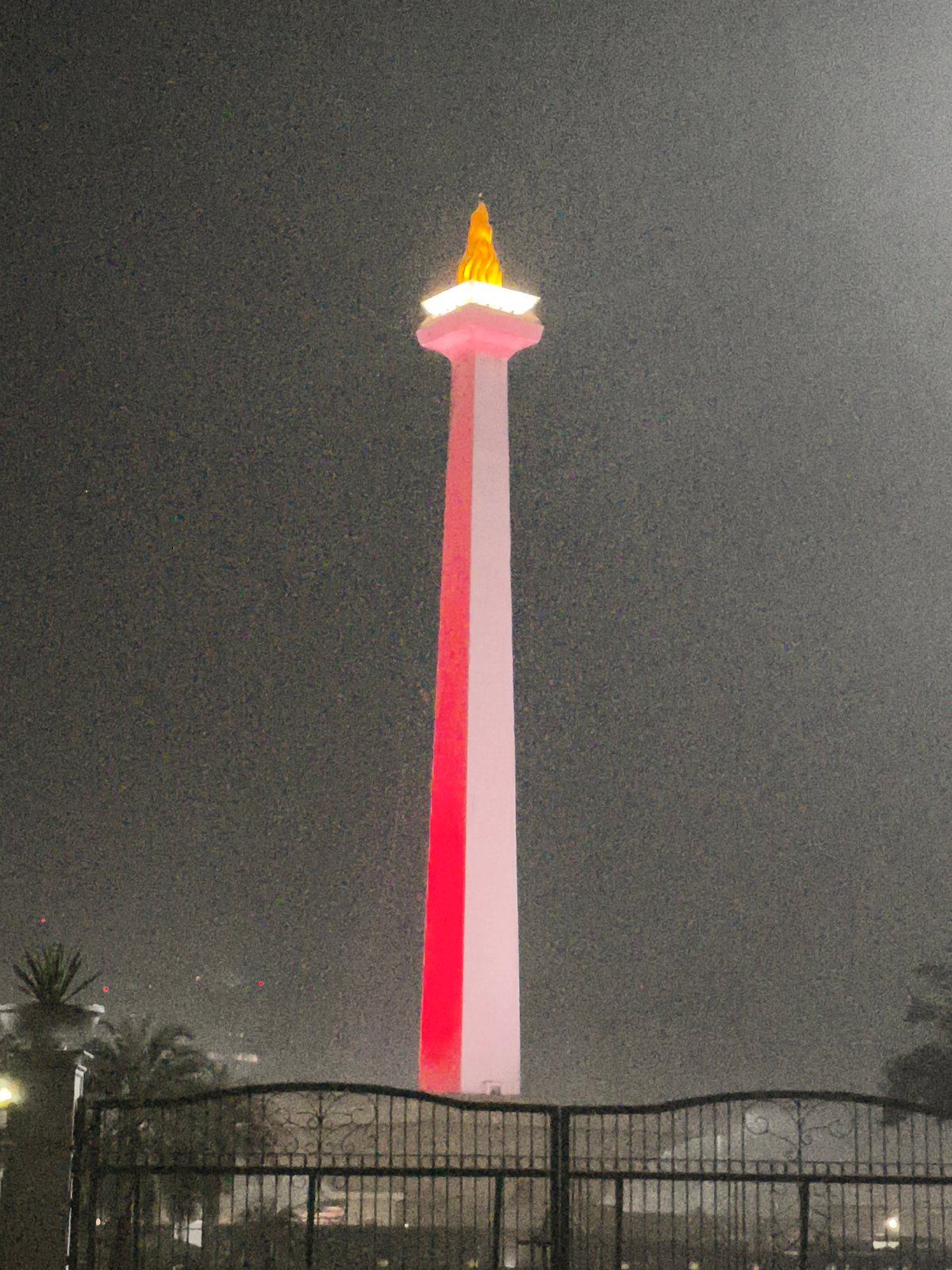 Monas tower illuminated through misty night in Jakarta
