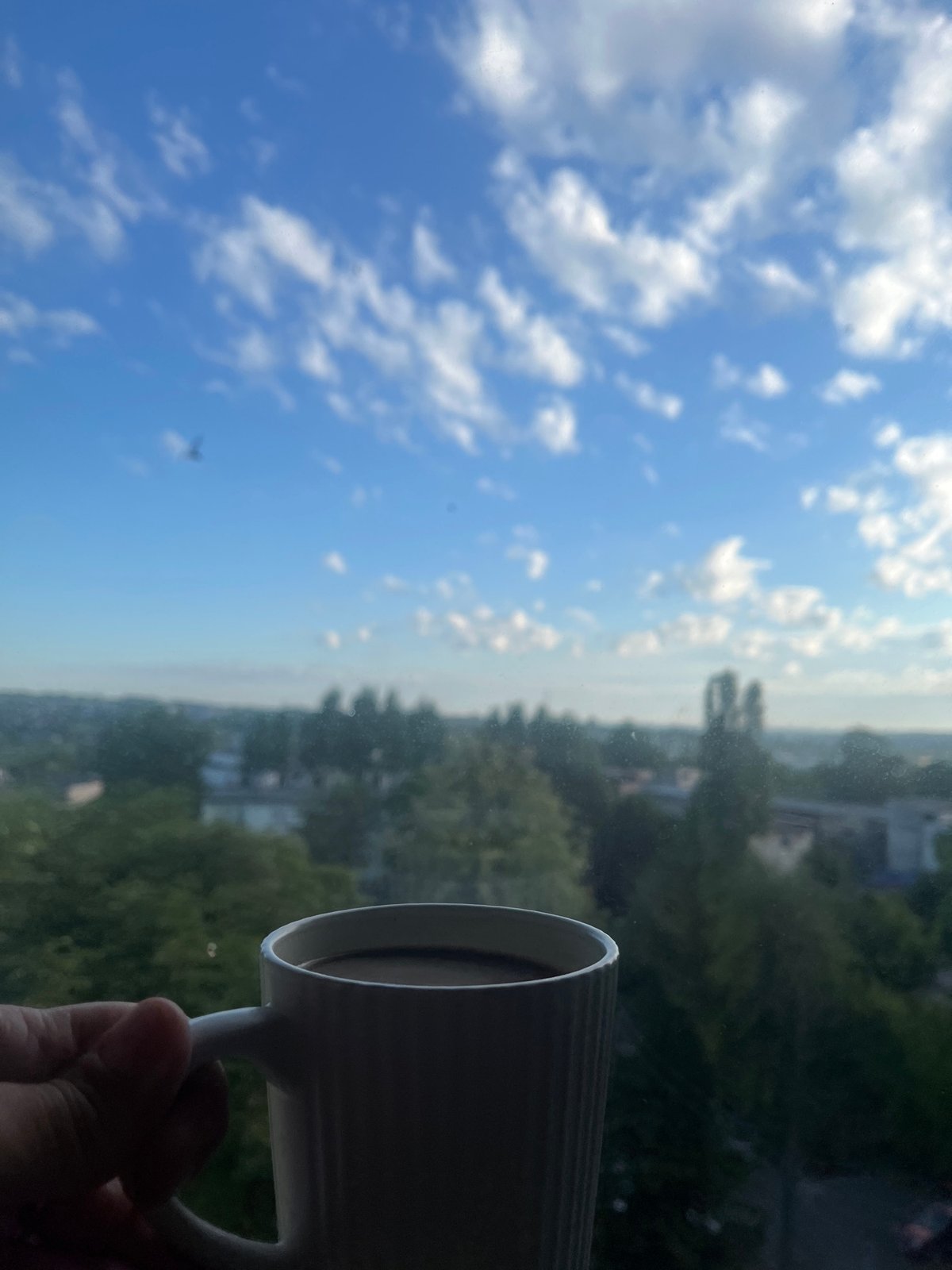 Coffee mug held up against a bright city skyline