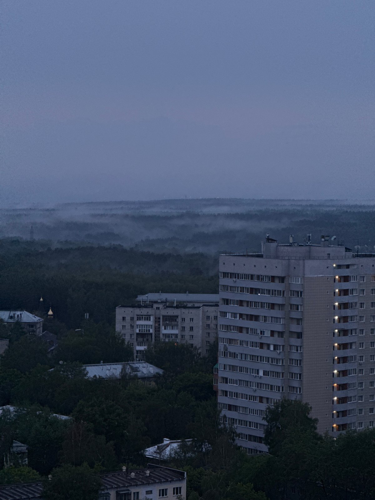 Novosibirsk skyline at twilight, green canopy meets residential blocks