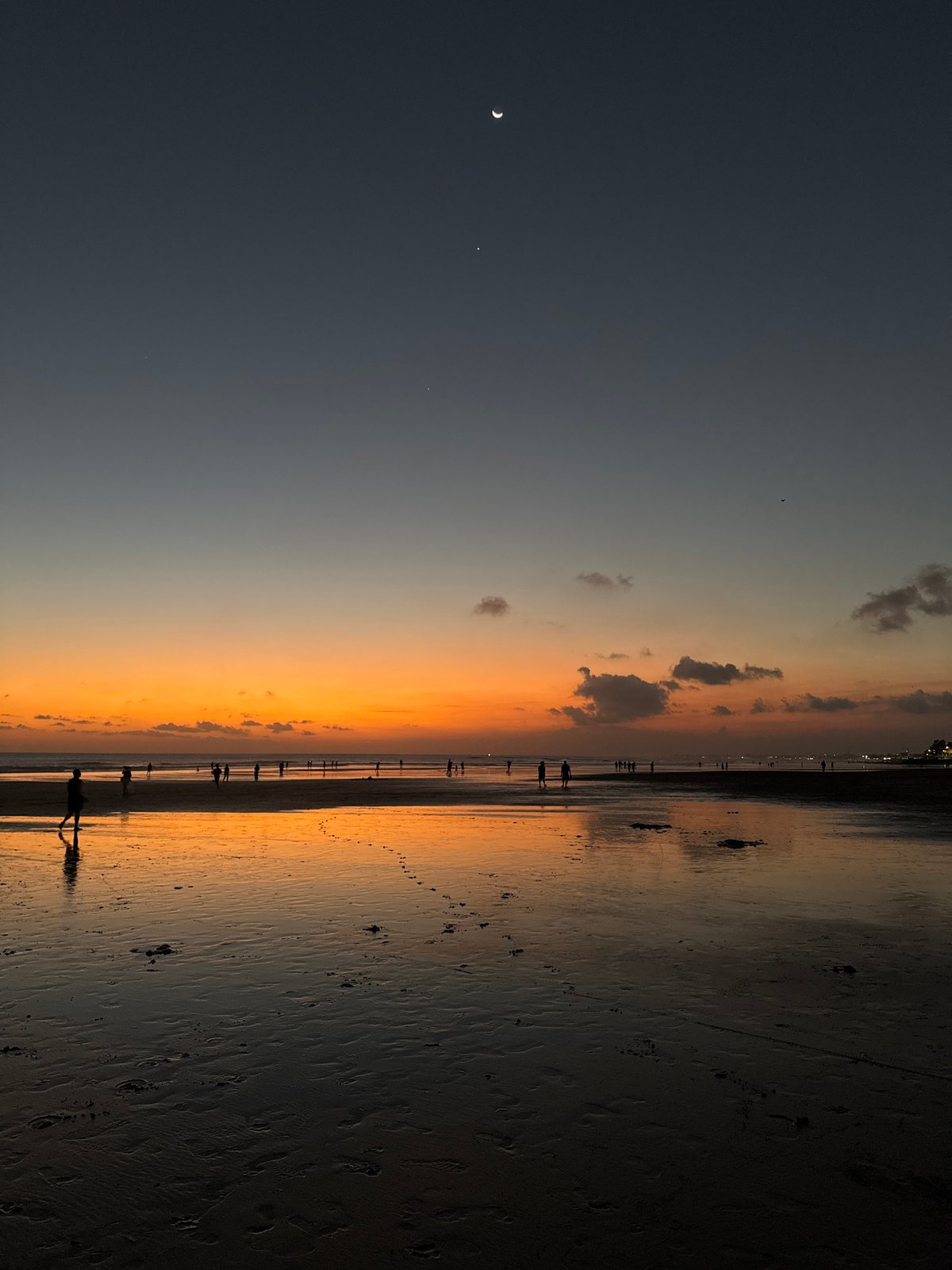 Sunset soccer and strollers on Kuta Beach's reflective shoreline