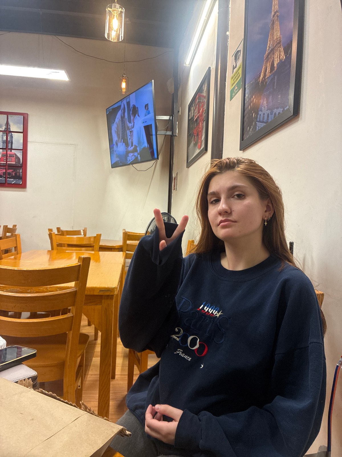 Woman in Paris 2024 sweatshirt poses at Mexican restaurant