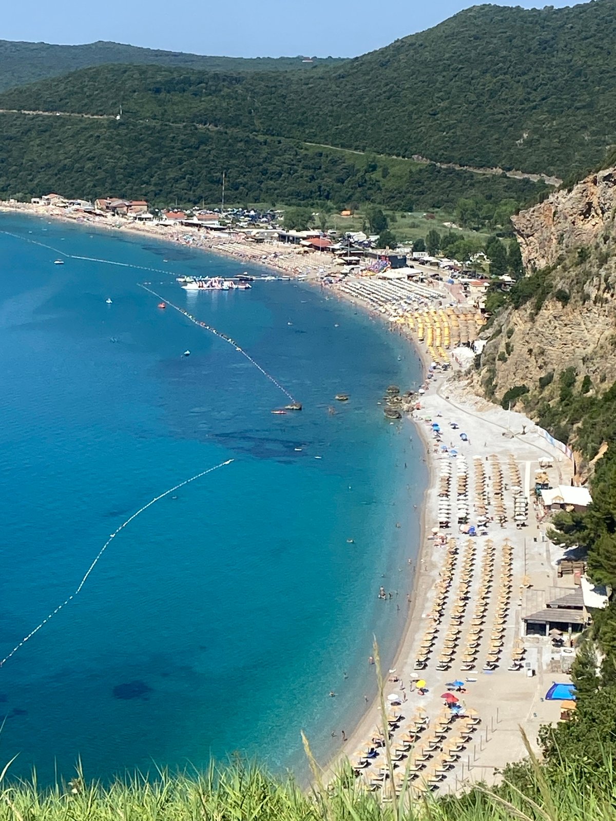 Crowded Montenegrin beach bay on a calm summer morning