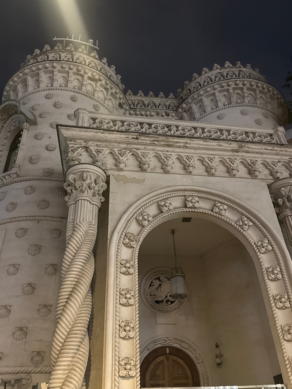 Ornate turreted building photographed at night, two angles