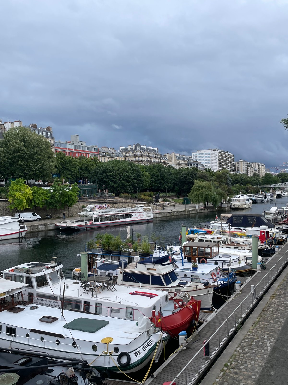 Houseboats line busy Parisian waterway under overcast skies