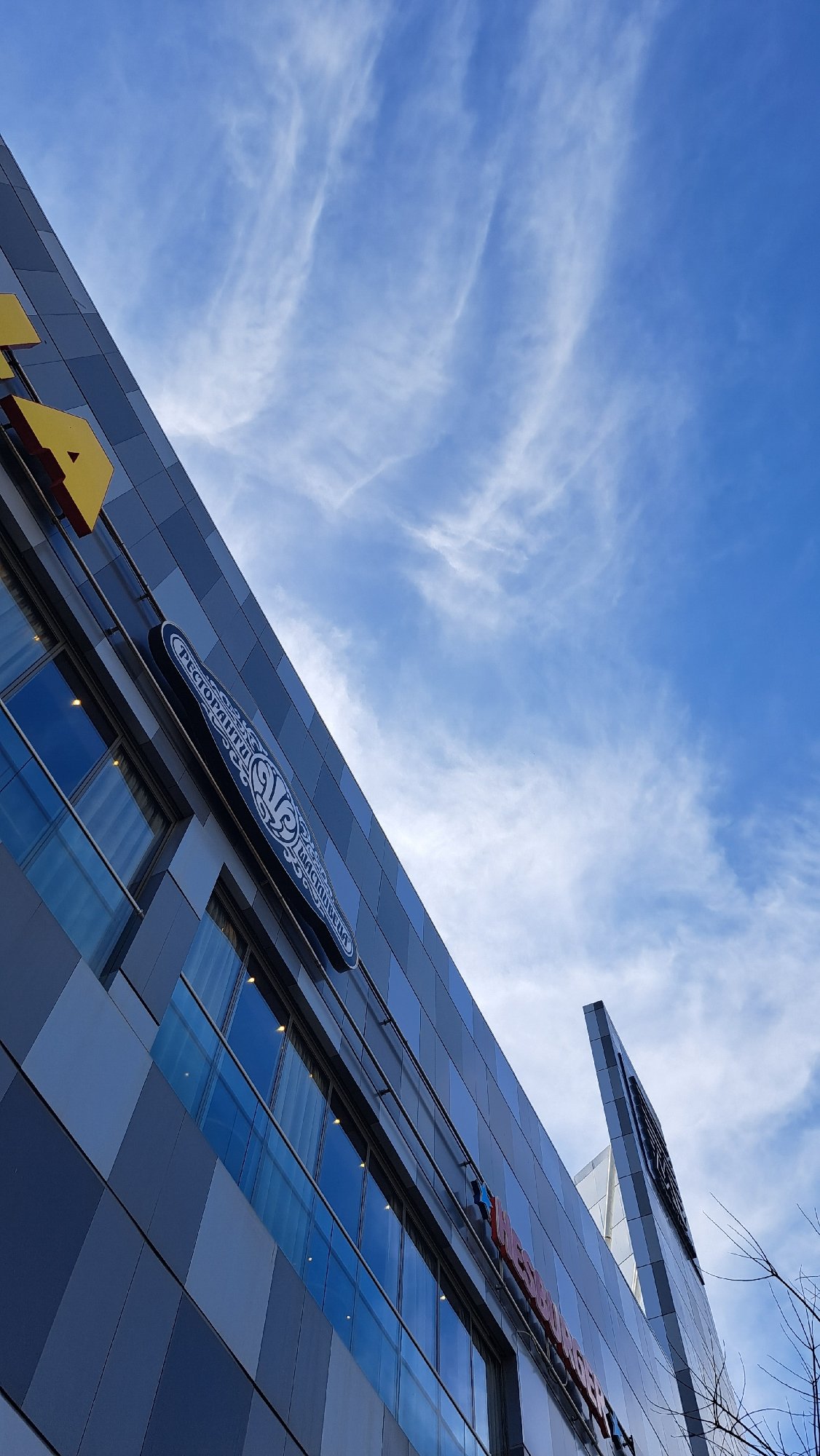 Modern grid-facade building photographed against blue sky with clouds