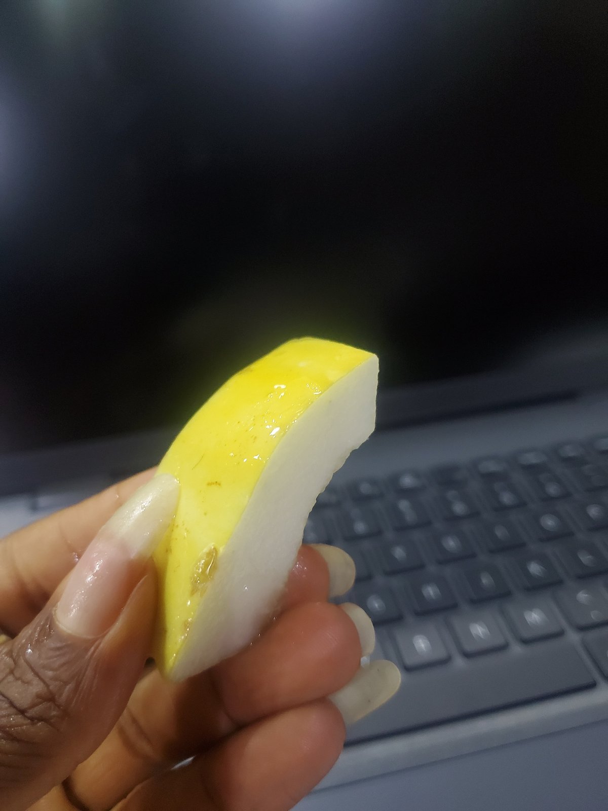Woman takes fruit break while working at laptop in Nigeria