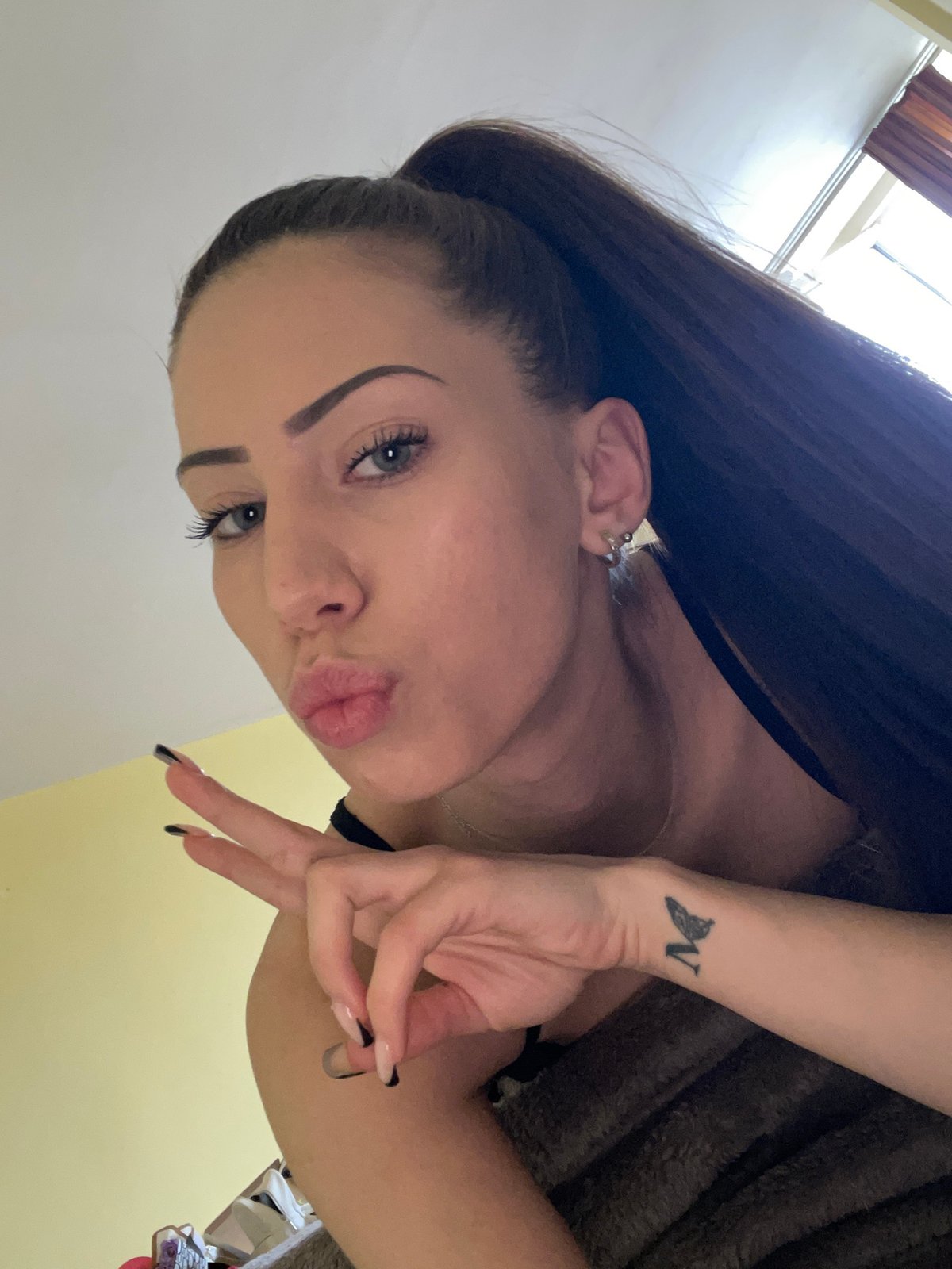 Woman takes selfies indoors, displays wrist tattoo