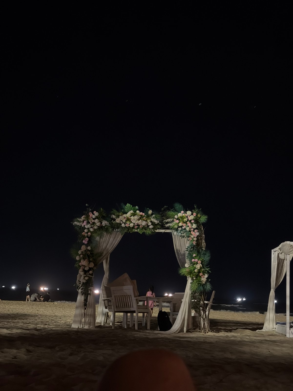 Nighttime beach celebration with floral archway in Đà Nẵng