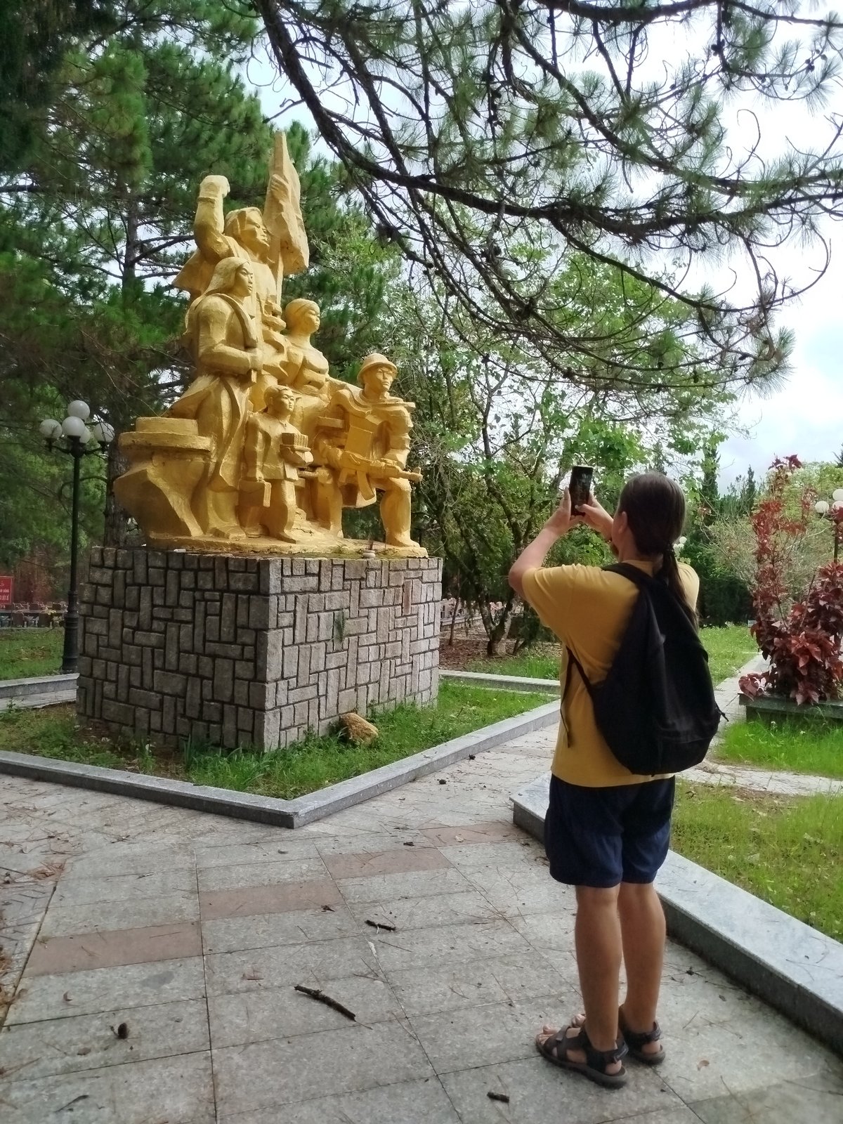 Visitor photographs monuments at Đà Lạt cemetery memorial park