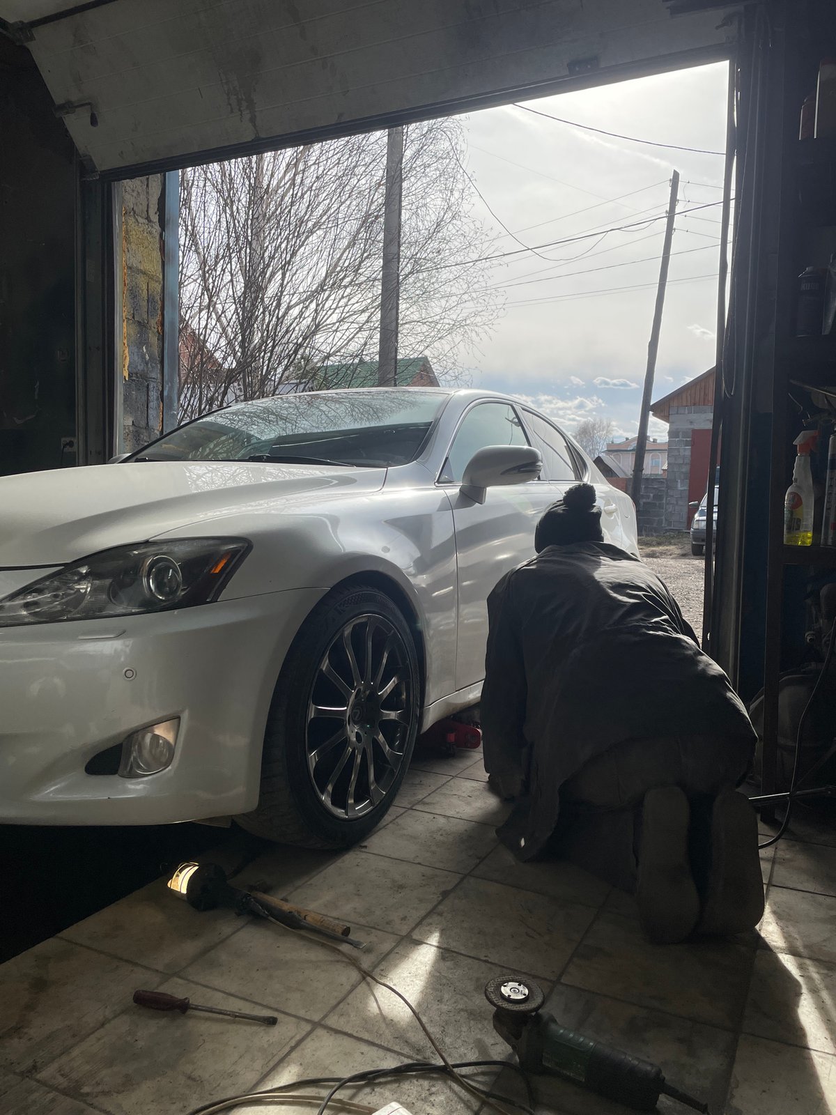 Mechanic repairs white Lexus brakes in Russian garage