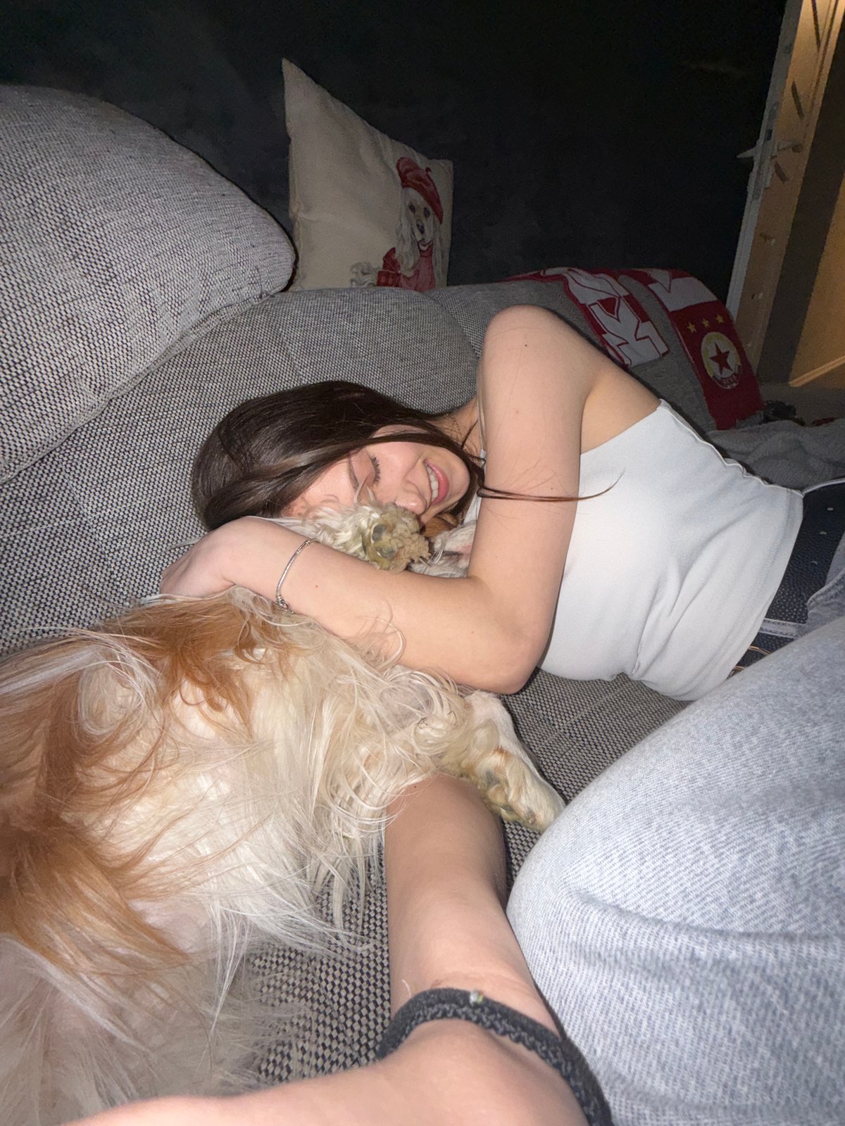 Woman cuddles with dog on sofa in Sofia
