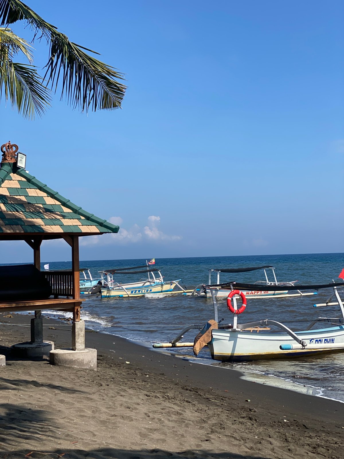 Black sand beach morning in Buleleng, boats and fruit