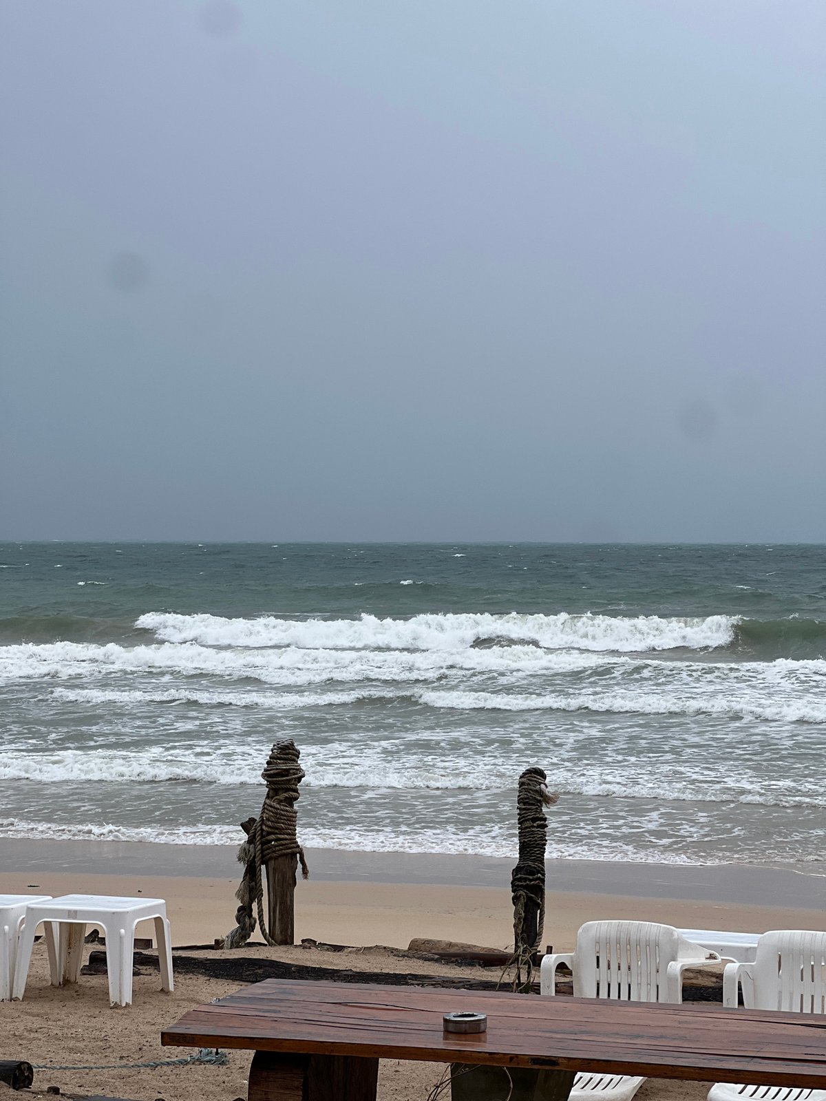 Empty beach under stormy skies with red warning flag flying