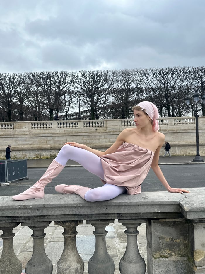 Young person sits on stone balustrade in Paris public area