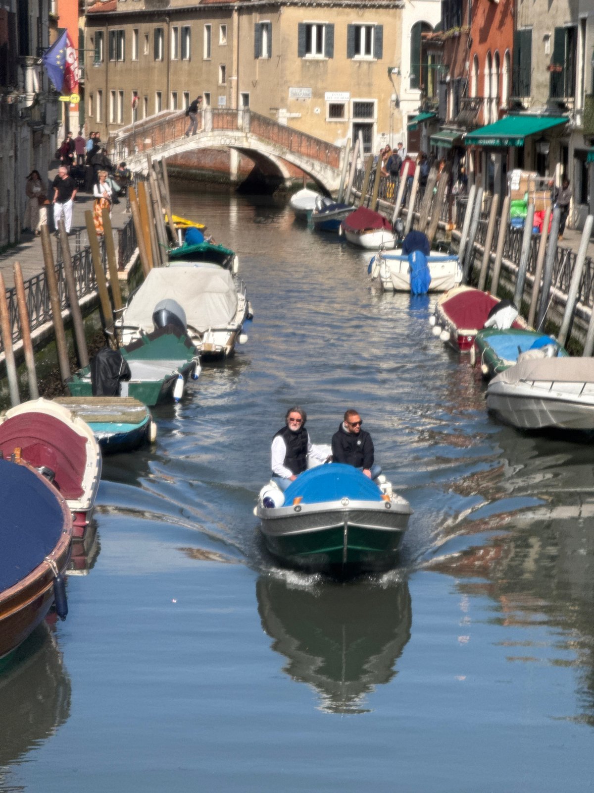 Motorboat travels Venice canal on overcast morning