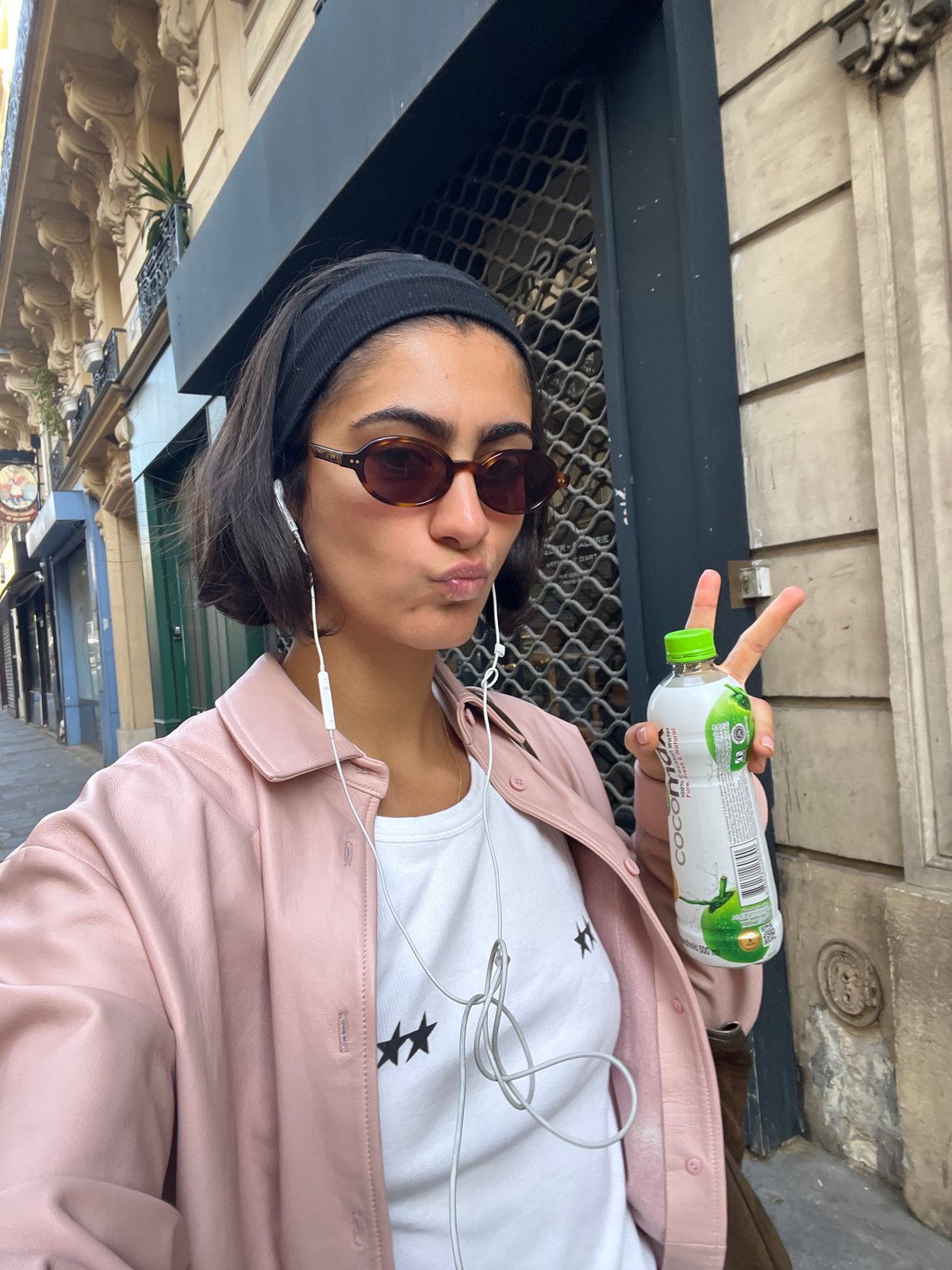 Woman takes selfies on Paris street wearing pink jacket