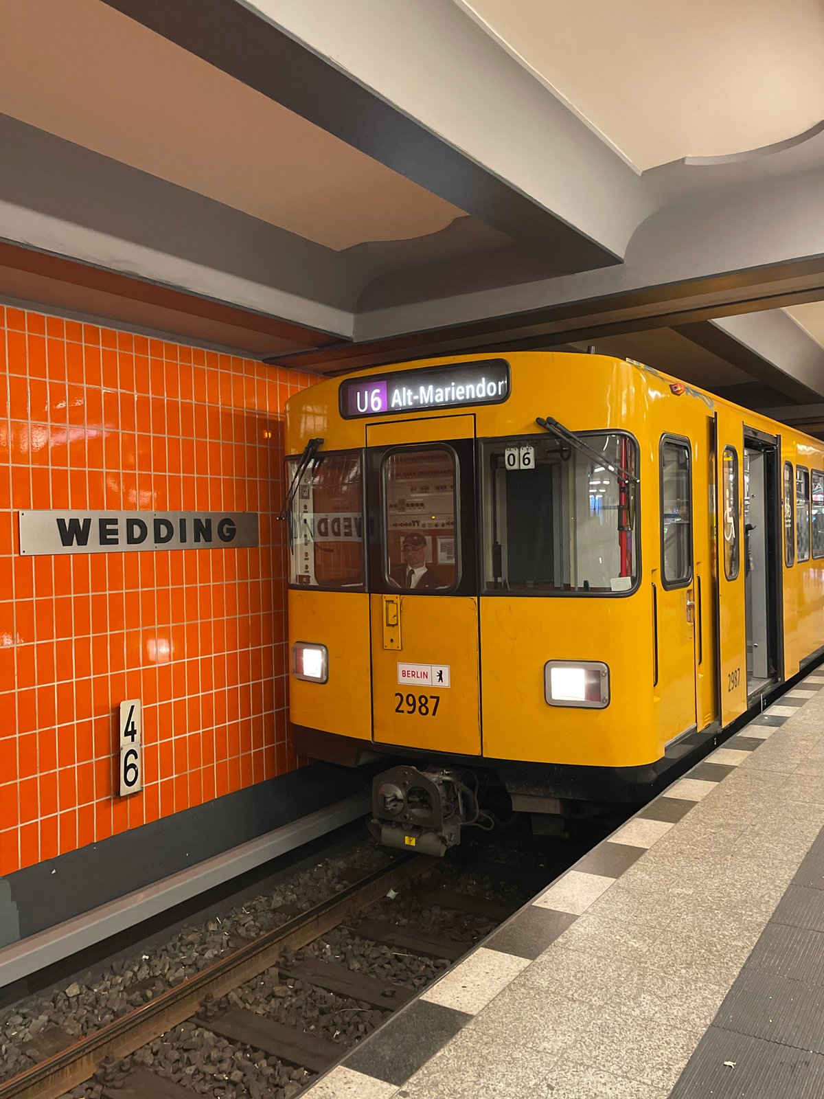 Yellow U6 subway train stops at Berlin station with passengers