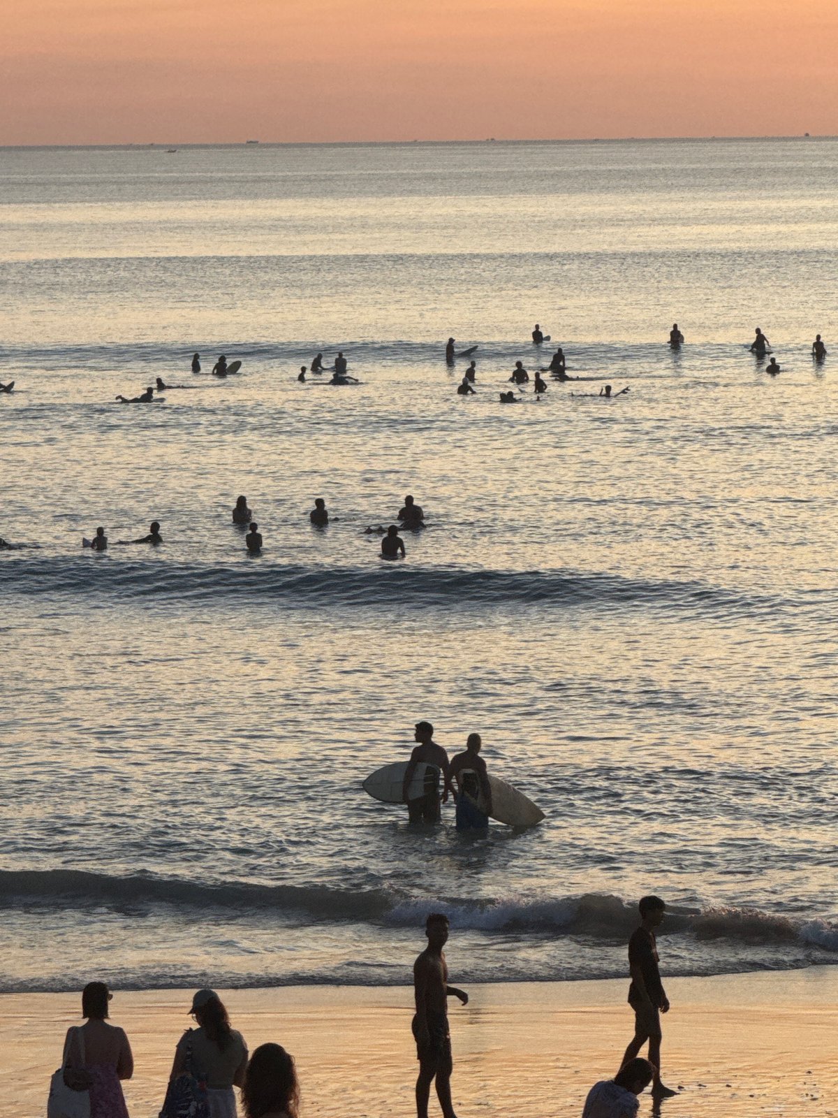 Surfers and beachgoers enjoy morning at Kuta Selatan beach