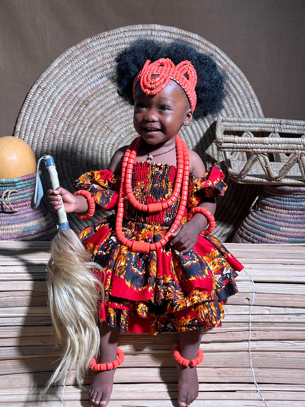 Child in traditional Nigerian ceremonial dress documented on woven mats