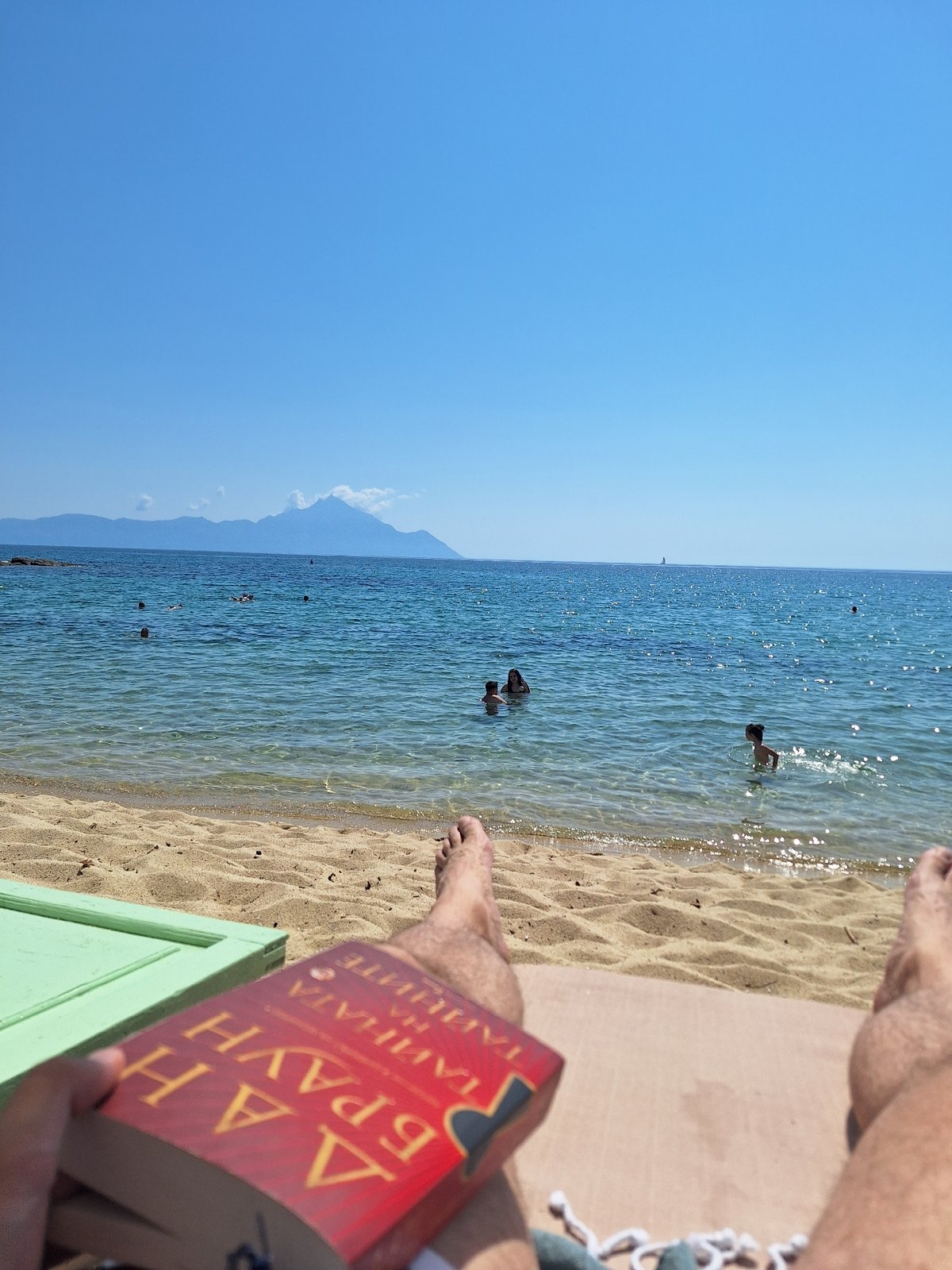 Lazy beach morning in Toroni, Greece — book, umbrella, calm sea.