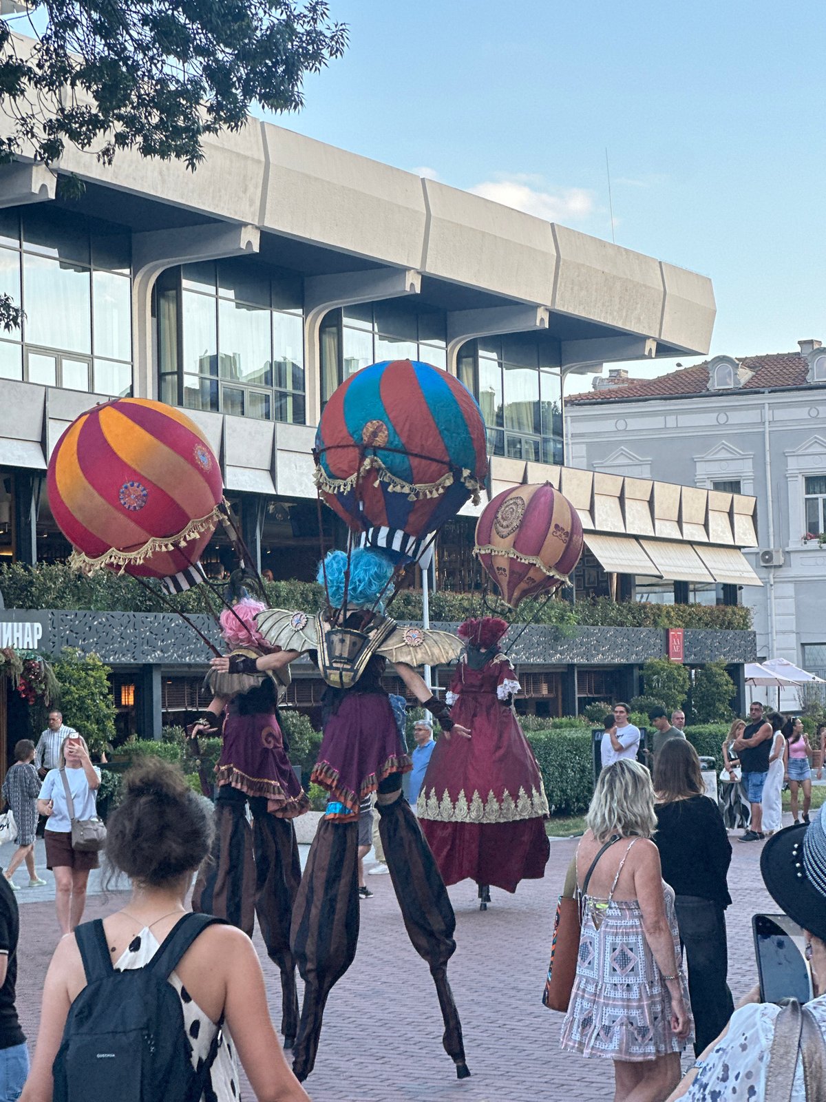Stilt performers in elaborate costumes entertain at an outdoor urban festival