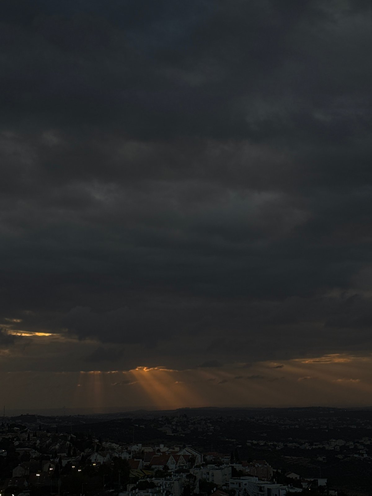 Sunlight breaks through dark clouds over urban landscape