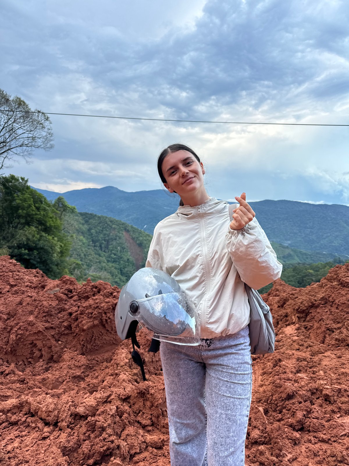 Woman motorcycles through muddy construction zone in rural Vietnam mountains