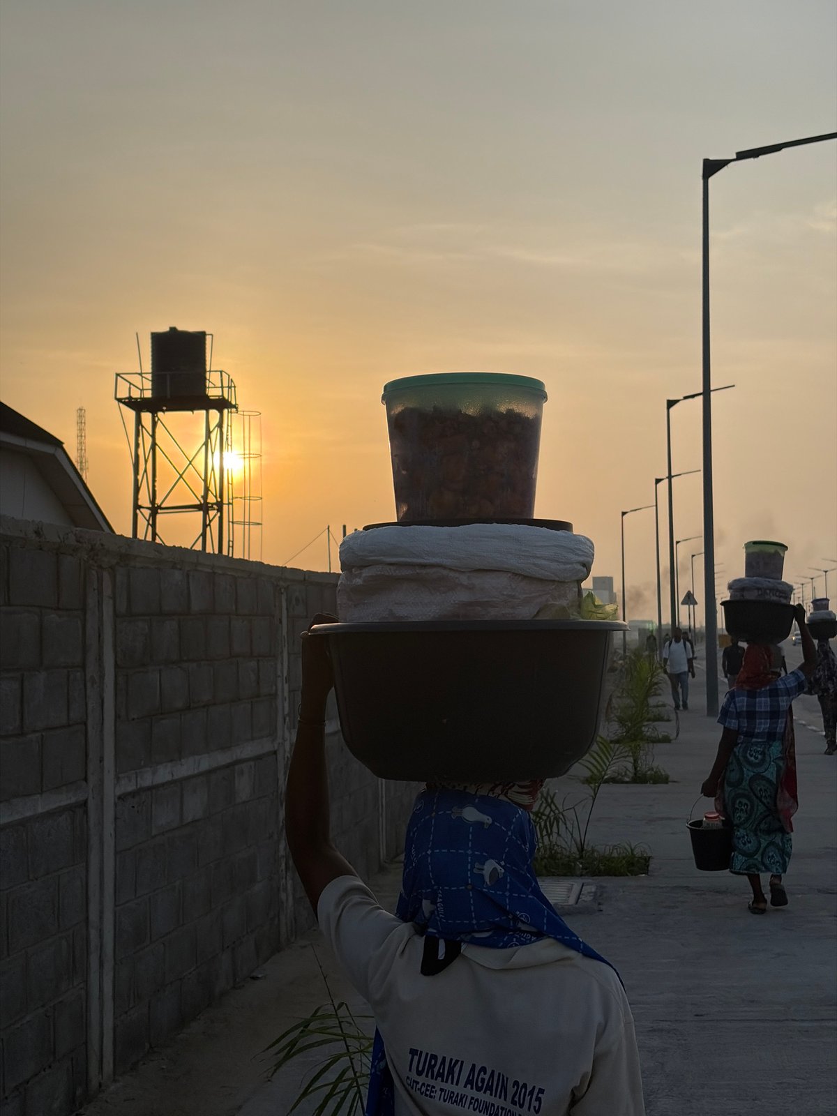 Women carry goods at sunrise in Nigerian village