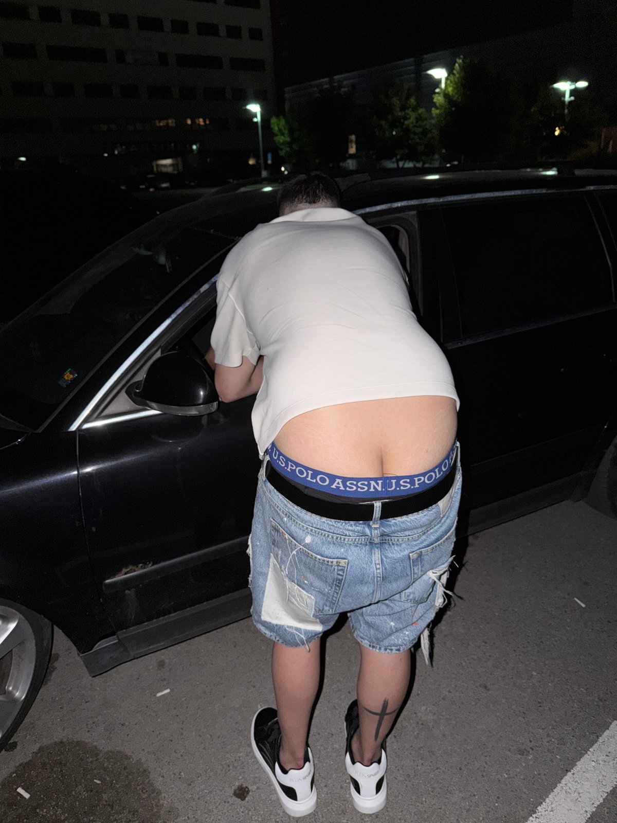 Young adults socialize in parking lot during evening gathering
