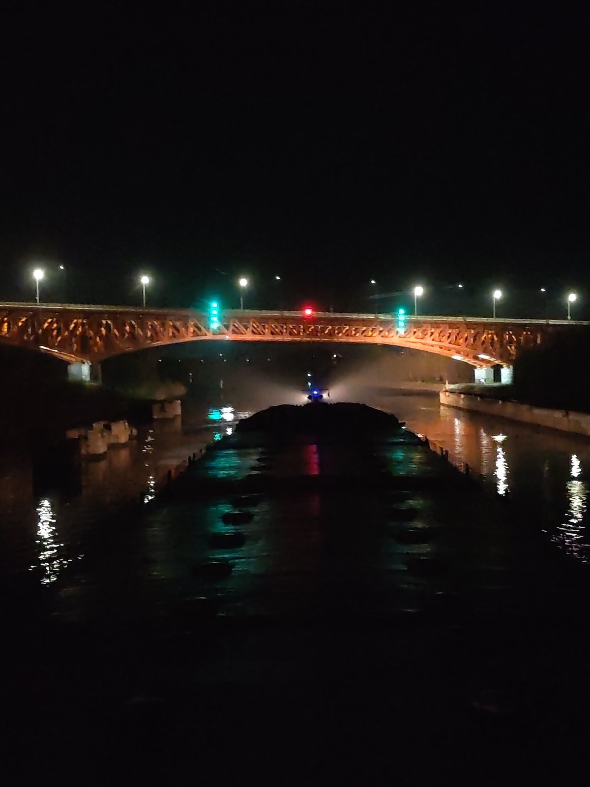 River cruise ships dock beneath illuminated bridge at night