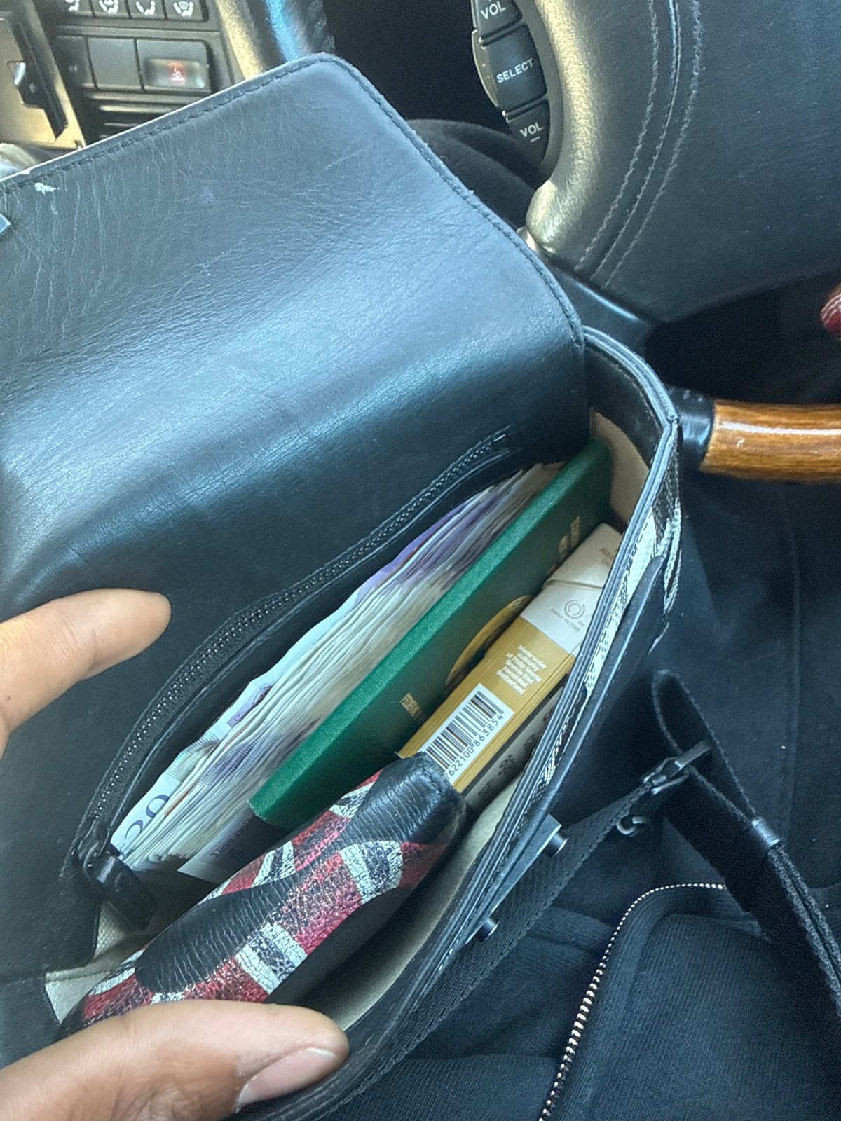 London resident examines black leather bag contents in vehicle
