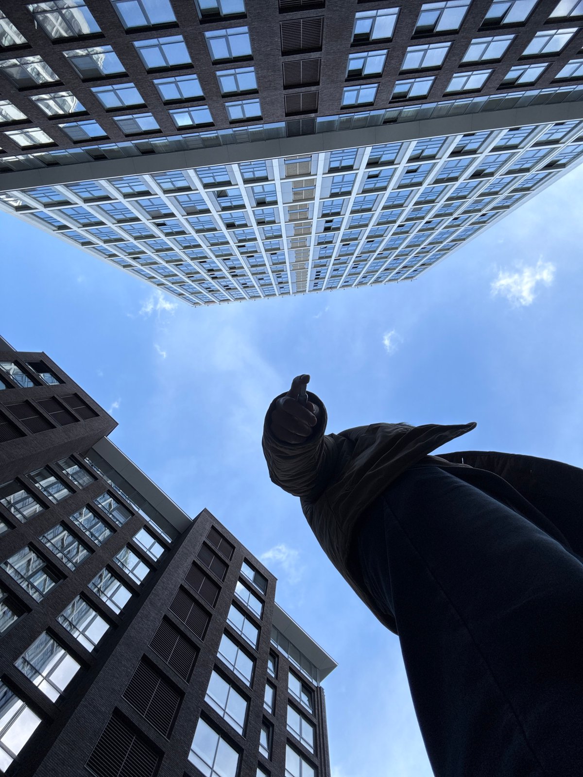 Person gazes skyward in Moscow courtyard amid modern towers