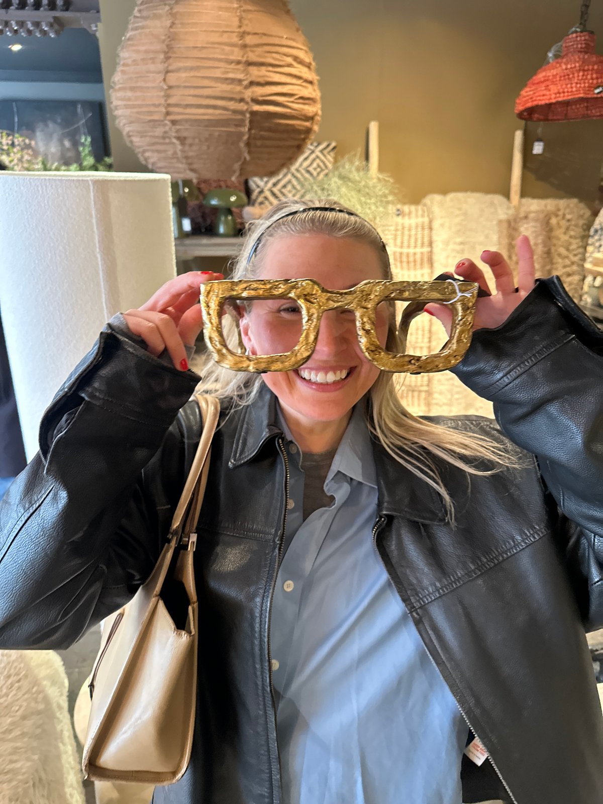 Woman poses with novelty gold D-shaped glasses in London