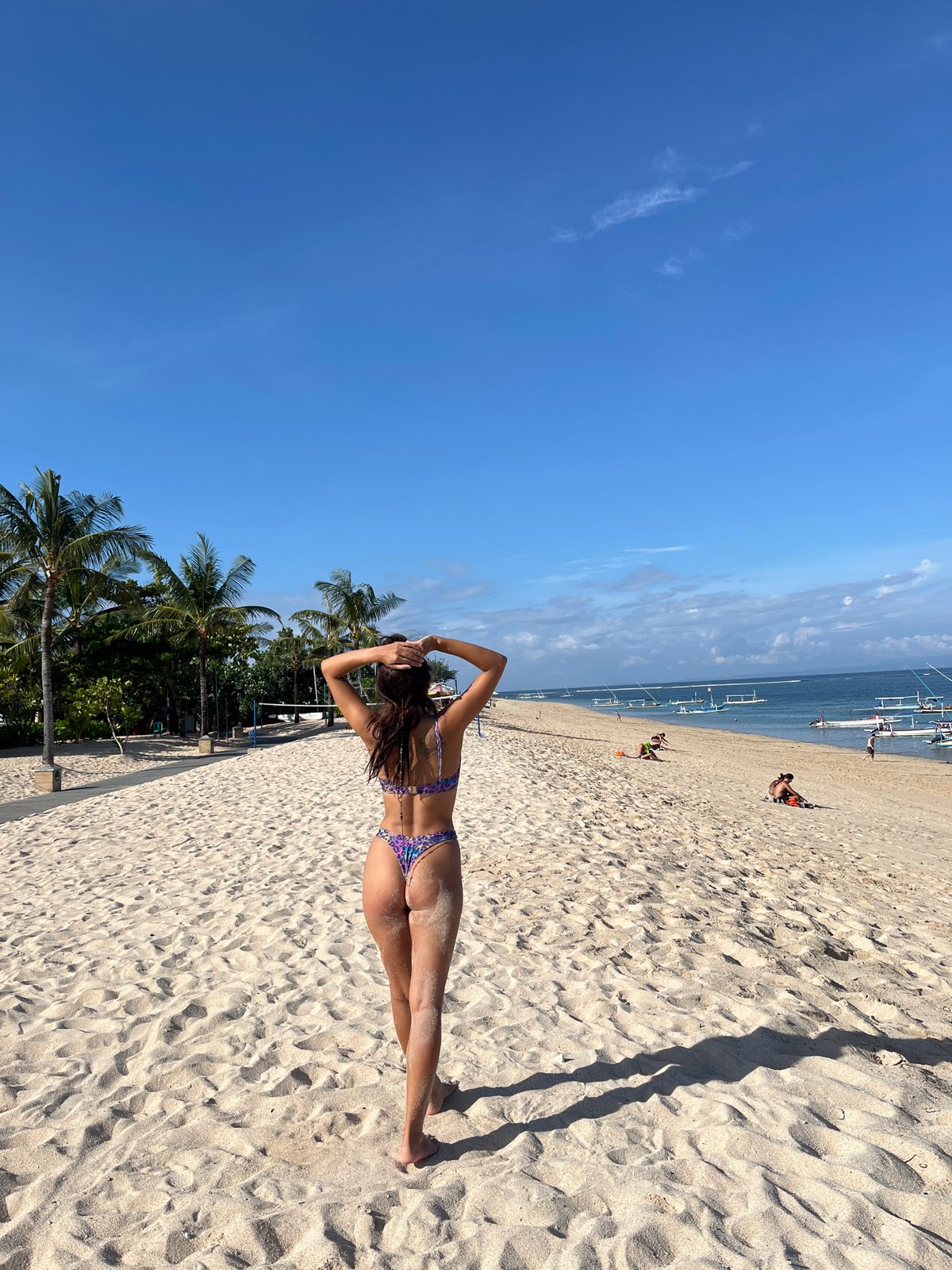 Woman sunbathes on Kuta Selatan beach under sunny skies