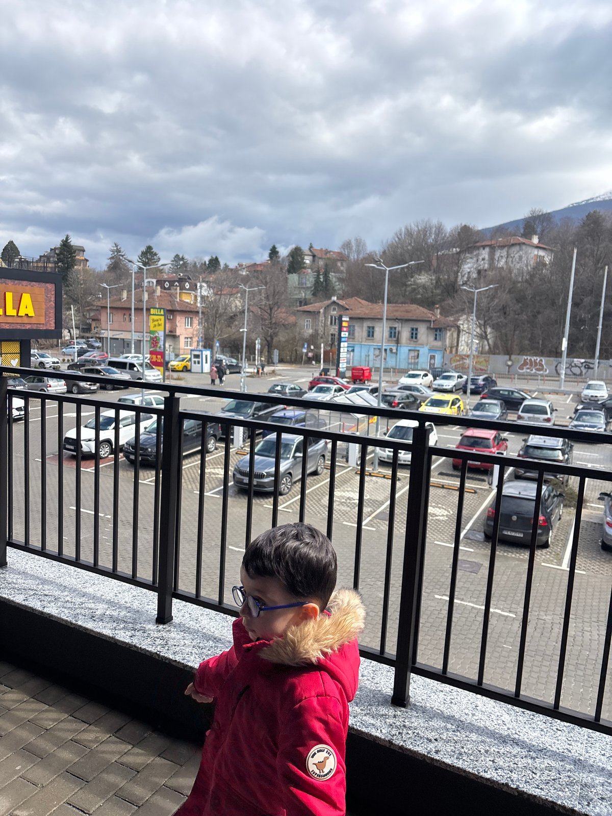 Child in red coat photographed at railing in Sofia