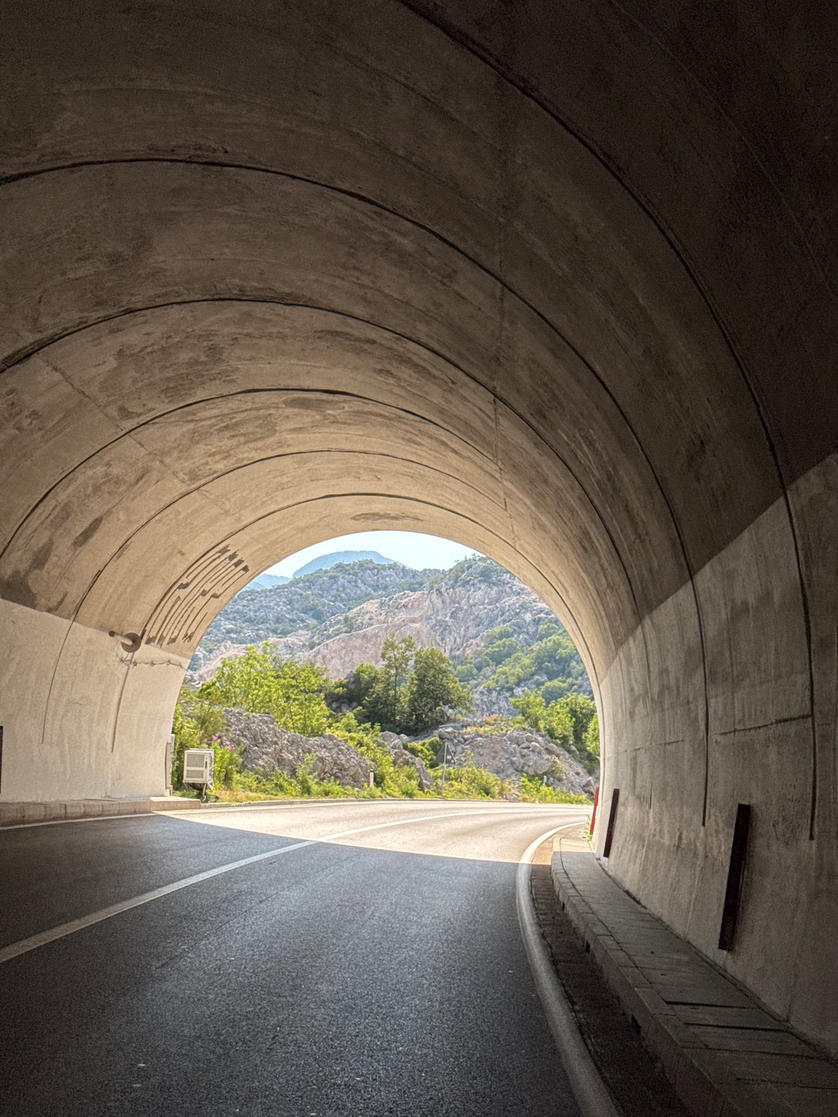 Tunnel exit opens onto rocky, green mountains near Risan