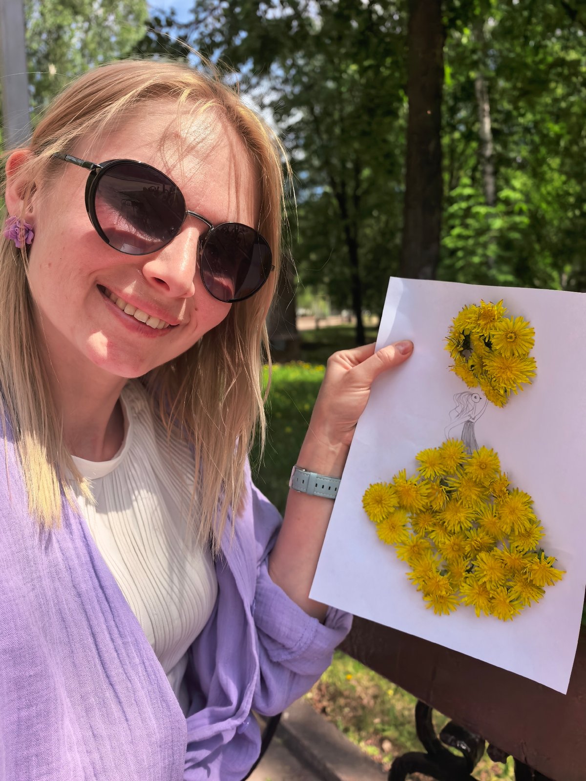 Woman creates dandelion art during park outing with baby