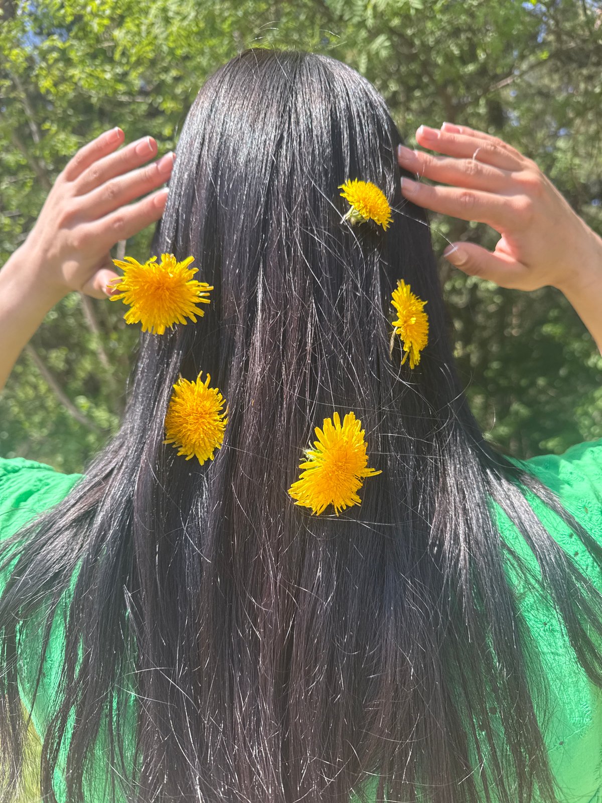 Person poses with dandelions in hair outdoors in Votkinsk