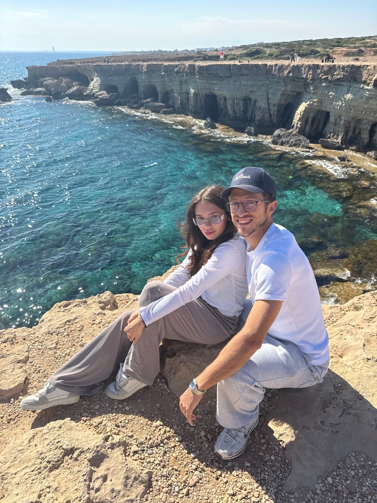 Couple relaxes on rocky cliff overlooking sea in Cyprus