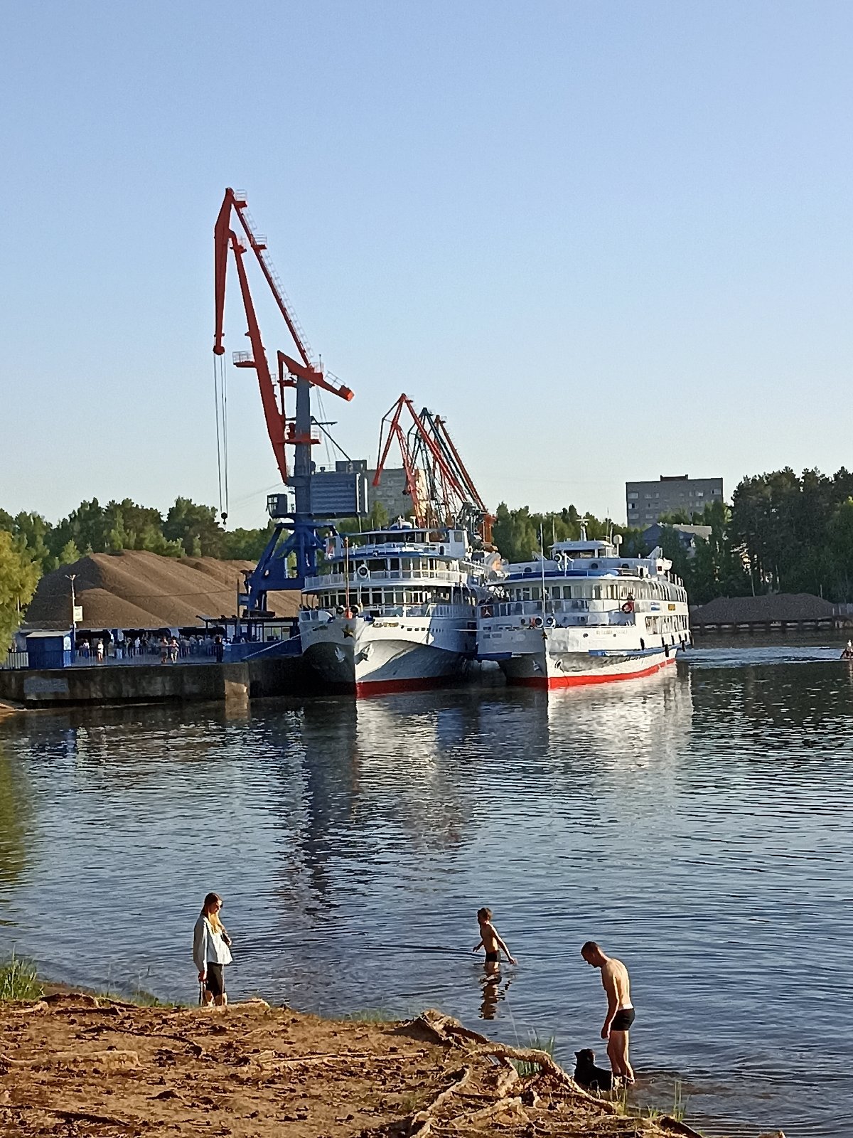 River cruise ships dock as passengers enjoy sunny waterfront afternoon