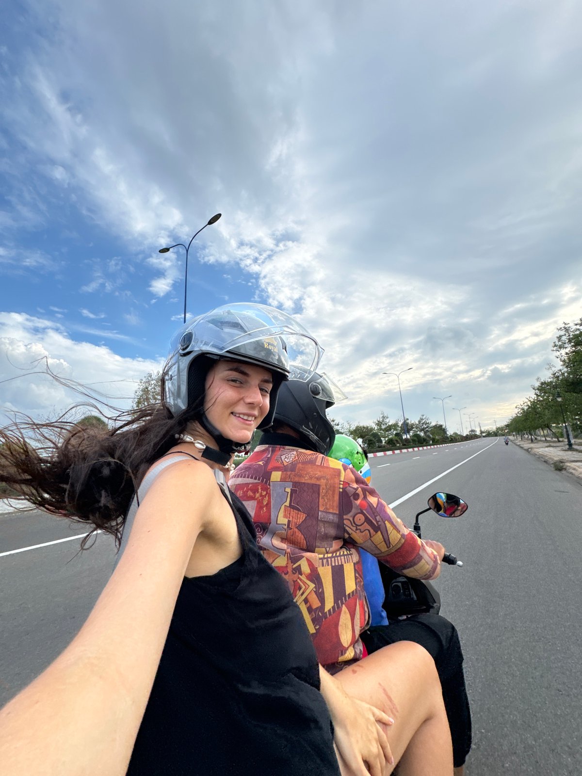 Woman takes selfie while riding motorcycle passenger in Vietnam