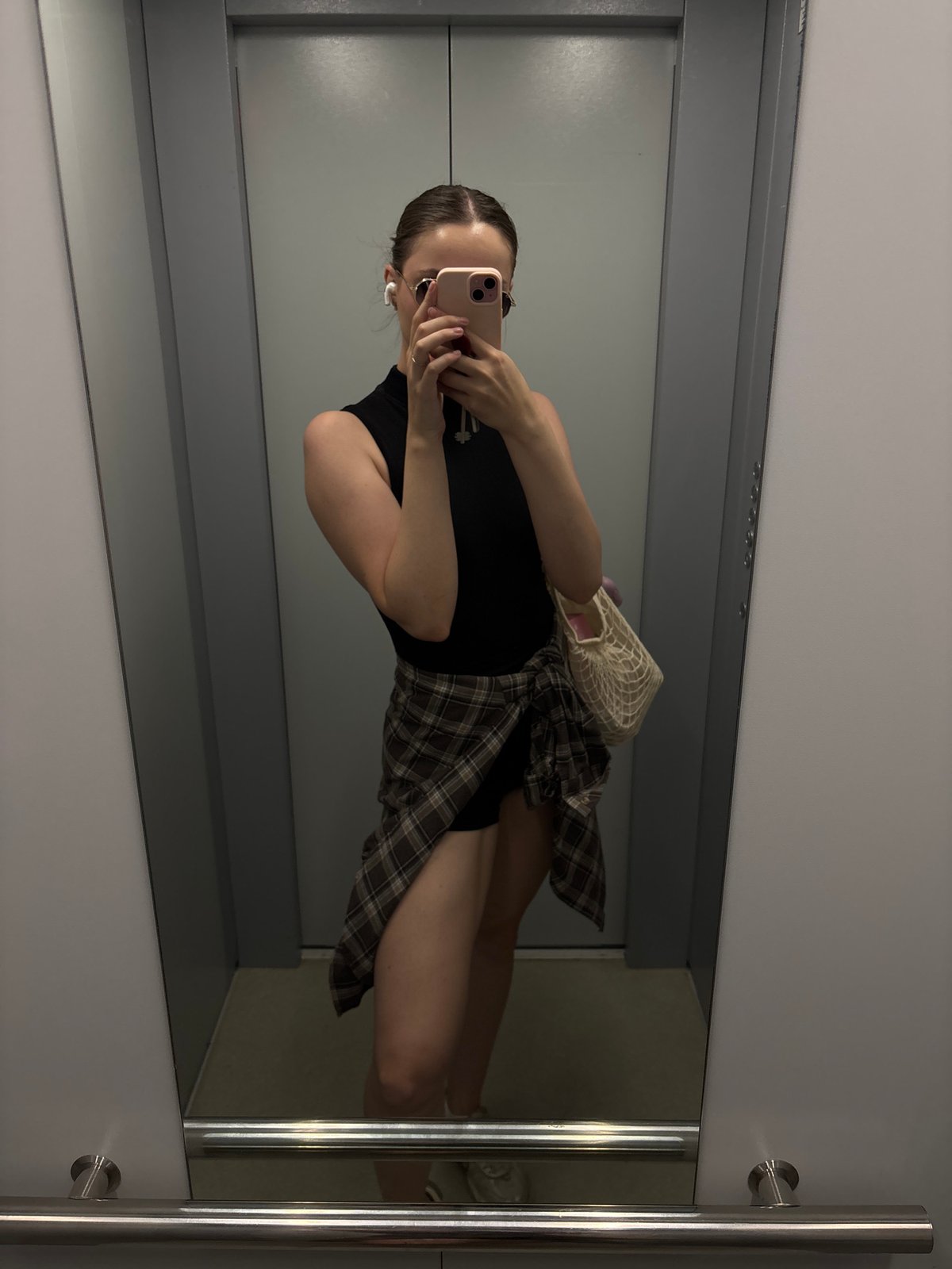 Elevator mirror selfie, low angle, full-body reflection.