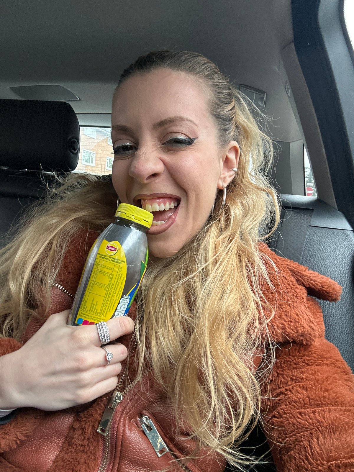 Woman enjoys iced tea in car in London