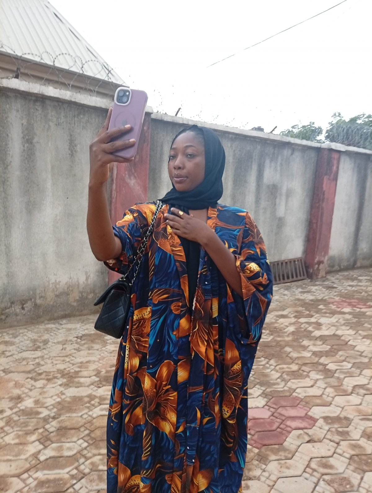 Woman takes selfie with lavender phone while wearing floral robe